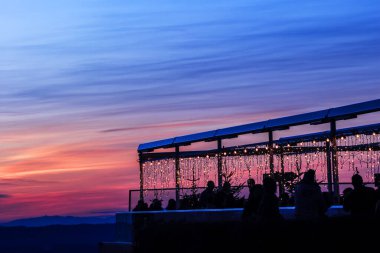 Uetliberg tepesindeki iyi aydınlatılmış restoranda insanlar yeni yılı kutlamak için akşam gün batımının tadını çıkarıyorlar, Zürih İsviçre