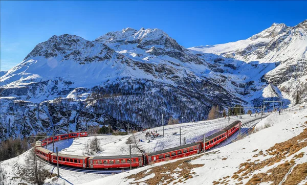 一列红色的火车在Rhaetian铁路轨道上通过时 在Berina山口高海拔的Alp Gruem有一条著名的180弯道 这是一张空中图像 图库图片