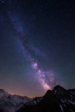 Samanyolu ve yıldızlar gece gökyüzünde Lauterbrunnen 'deki İsviçre Alpleri üzerinde Jungfrau tepeleri ile