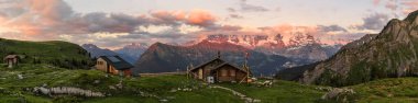 İsviçre Alpleri 'nin yüksek rakımlı panoraması ve dağ kulübeleri altın günbatımı saatlerinde Eiger, Monch ve Jungfrau tepelerinin arka planına sahip gezginler için.