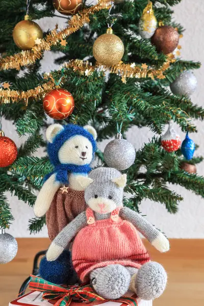 Self knitted kitty cat and teddy bear under the beautifully decorated Christmas tree