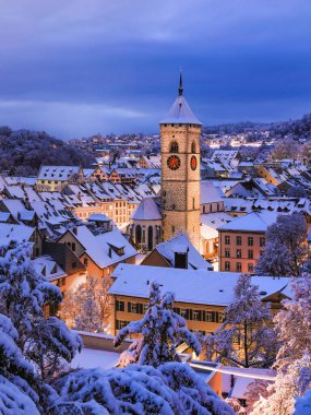 Twilight view of the old Swiss city of Schaffhausen town in winter with Christimas season illumination and the with fresh snow-covered roofs at dusk  clipart