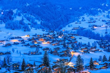 Grindelwald köyleri soğuk kış mevsiminde kar ile kaplı ahşap Chalet 'lerle İsviçre Alplerinde mavi saatlerde