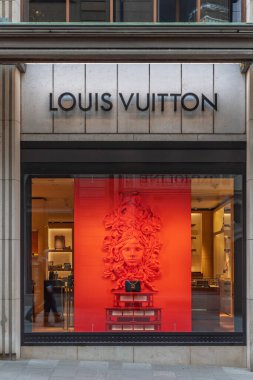 Basel, İsviçre - Nisan 08. 2024: Lüks moda markası Louis Vuitton 'un güçlü kırmızı arka planda bir kadın maskesiyle benzersiz vitrini.