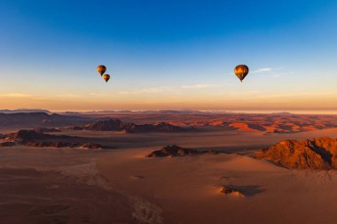 Namibya - 11 Temmuz. 2024: Namibya kırmızı kum tepeleri üzerinde sabah sıcak balon uçuşu. Çölde bir turist saldırısı.