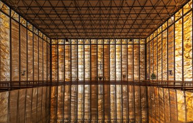 The Roman Catholic church St. Pius (built in 1966) with wall reflection over a stone table. The walls are made of 888 slabs of 28mm thick, translucent marble illuminate the interior. clipart