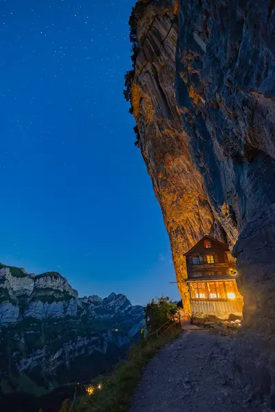 stock image Ebenalp, Switzerland - August 10. 2024: The 160 year old mountain hut Aescher Gasthaus in blue hou sunset time, Ebenalp, Switzerland