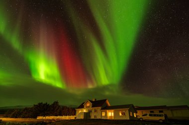 Hvistserkur, Iceland - October 10, 2024: Colorful aurora or northern light over the hostel Osar in the night clipart