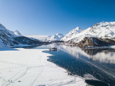 Aerial view of the frozen lake of Silsersee with people walking on the lake surface - Maloja and Plaun da Lej in St. Moritz, Switzerland clipart