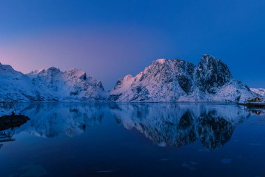 Olstind mountain peak above the fjord with reflection in the quiet blue hour with the last sun shine, Rhine, Lofoten clipart