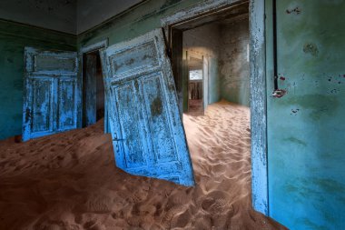 Günbatımında Kolmanskop 'ta yeşil duvarı olan terk edilmiş ev. Güney Namibya' da terk edilmiş elmas madeni köyü..