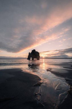 Hvisterkur kaya oluşumu, Rhino olarak da bilinir, güneşin doğuşuyla birlikte, siyah kumsalın yansımasıyla - rüya gibi ve sessiz bir parıltıyla.