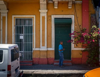 SANTO DOMINGO - 30 Mart - 30 Mart 2023 'te Dominik Cumhuriyeti' nin Santo Domingo kentinde bir adam renkli eski mimariyle sokakta yürüyor.
