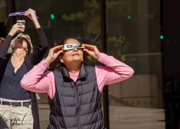 ニューヨーク April 4月8日 マンハッタンのダウンタウンで太陽の日食を見ている2人の女性 ストックフォト