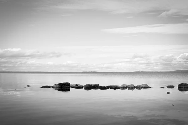 黒と白の水の中の岩で穏やかな湖を見下ろす — ストック写真