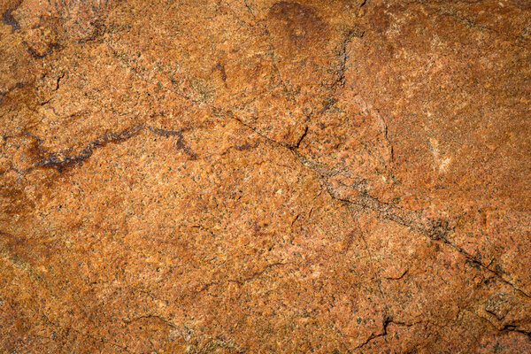 Old orange stonewall in closeup with cracks