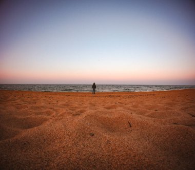 İnsanoğlunun küçüklüğü. Sahilde denizin önünde duran tanınmayan biri. Perspektif azalıyor.