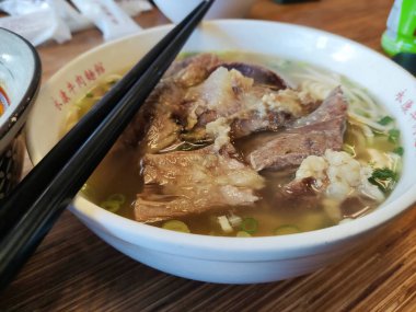 Taipei, Taiwan- 3 Dec, 2022: Braised beef noodle soup with chopsticks in Taiwan. Taiwanese beef noodle soup is a rich and comforting bowl of noodles topped with tender braised beef