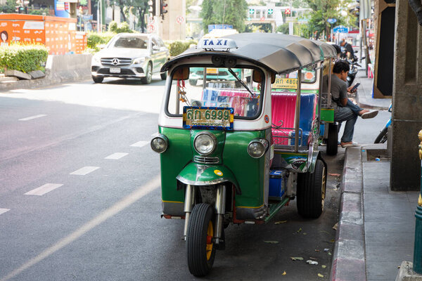 Bangkok, Thailand- 13 Feb, 2023: Traditional tuk-tuk on the road in Bangkok. Tuk tuks are motorized 3-wheeled rickshaws that ferry passengers around