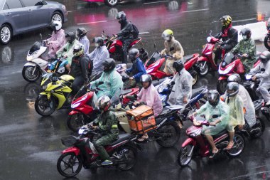 Bangkok, Tayland - 15 Şubat 2023: Bangkok 'ta yağmurlu bir günde insanlar motosiklete biniyor.