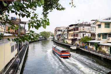 Bangkok, Tayland - 17 Şubat 2023: nehir taksisi yolcuları taşımak için Bangkok kanalı boyunca seyahat eder. Tekneler ve feribotlar Bangkok 'ta dolaşmak için uygun ve ilginç bir yol.