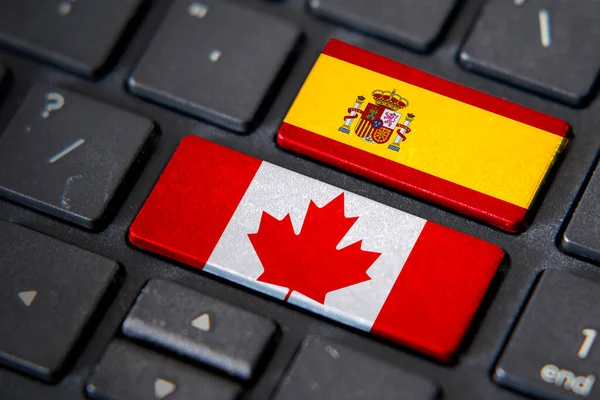 Canada and Spain flags on computer keyboard. Relationship between two countries.