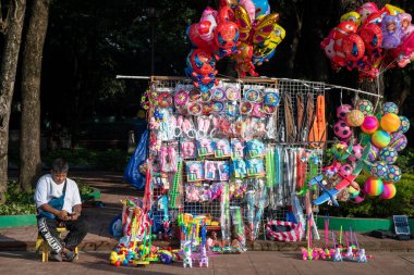 Manila, Filipinler- 14 Ekim 2023: Rizal Park, Manila 'da müşteri bekleyen oyuncak satıcısı. Manila, Ermita 'da bulunan tarihi bir şehir parkı.