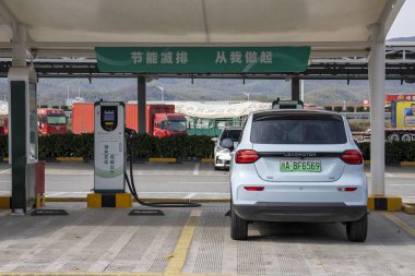 Nanjing, Çin - 30 Kasım 2023: yoldaki şarj istasyonundan şarj olan elektrikli araba. Çin dünyanın en hızlı büyüyen EV pazarlarından birine sahip.