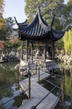 Suzhou, Çin - 7 Aralık 2023: Çin pavyonu ve Çin 'in Suzhou kentindeki Lion Grove Garden' daki gölet üzerindeki köprü. Burası UNESCO Dünya Mirasları Alanı olarak tanınıyor.