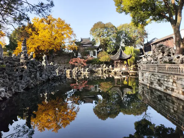 Suzhou, Çin - 7 Aralık 2023: Çin 'in Suzhou kentindeki Lion Grove Garden' daki kaya ve göl üzerindeki sonbahar manzarası. Diğer klasik Suzhou bahçeleri UNESCO olarak tanınır.