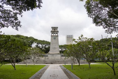 Singapur-12 Ocak 2024: Gri taş Cenotaph savaş anıtı, Esplanade Parkı 'nda yeşil yapraklarla çevrili, yoğun gri gökyüzü yağmuru altında. 2. Dünya Savaşı.