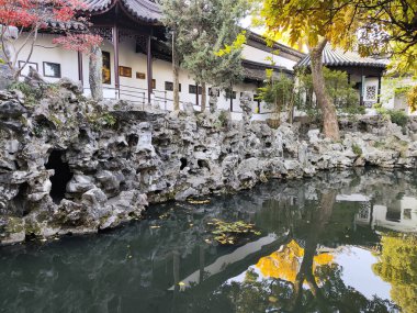 Suzhou, Çin - 7 Aralık 2023: Çin 'in Suzhou kentindeki Lion Grove Garden' daki kaya ve göl üzerindeki sonbahar manzarası. Diğer klasik Suzhou bahçeleri UNESCO olarak tanınır.