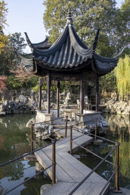 Suzhou, Çin - 7 Aralık 2023: Çin pavyonu ve Çin 'in Suzhou kentindeki Lion Grove Garden' daki gölet üzerindeki köprü. Burası UNESCO Dünya Mirasları Alanı olarak tanınıyor.
