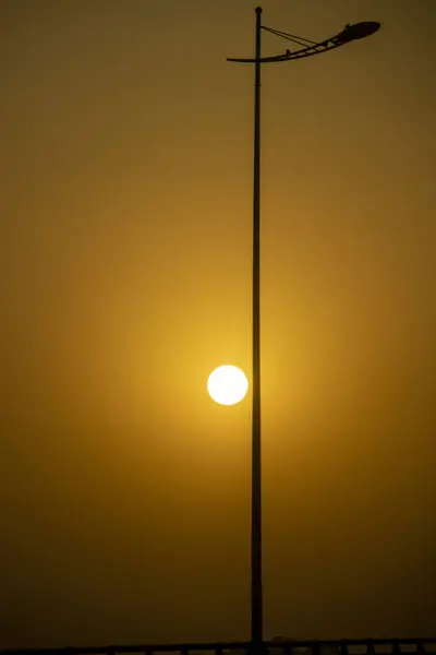 Golden sun during sunset and lamp post on the street