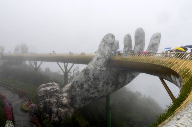Danang, Vietnam- 27 Feb, 2028: View in fog of the Golden Bridge on Ba Na Hills in Da Nang on rainy day clipart