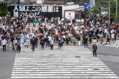 Tokyo, Japonya - 12 Mayıs 2024: İnsanlar Shibuya, Tokyo 'da işlek kavşağı geçiyor. Burası dünyanın en işlek kavşaklarından biri. (kasıtlı olarak insanların hareketlerini göstermek için bulanık)