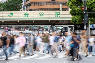 Tokyo, Japonya - 12 Mayıs 2024: İnsanlar Shibuya, Tokyo 'da işlek kavşağı geçiyor. Burası dünyanın en işlek kavşaklarından biri. (kasıtlı olarak insanların hareketlerini göstermek için bulanık)