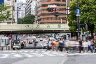 Tokyo, Japonya - 12 Mayıs 2024: İnsanlar Shibuya, Tokyo 'da işlek kavşağı geçiyor. Burası dünyanın en işlek kavşaklarından biri. (kasıtlı olarak insanların hareketlerini göstermek için bulanık)