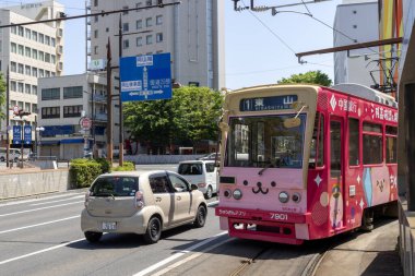 Okayama, Japonya - 10 Mayıs 2024: Okayama Elektrik Demiryolu tramvayı Okayama İstasyonu önündeki yolda ilerliyor.