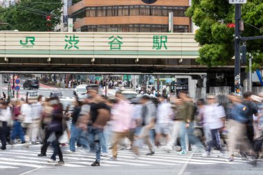 Tokyo, Japonya - 12 Mayıs 2024: İnsanlar Shibuya, Tokyo 'da işlek kavşağı geçiyor. Burası dünyanın en işlek kavşaklarından biri. (kasıtlı olarak insanların hareketlerini göstermek için bulanık)