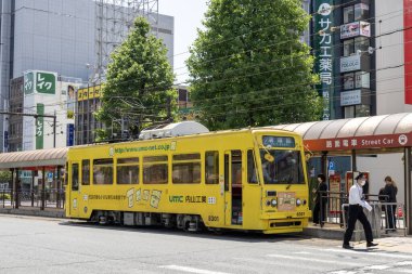 Okayama, Japonya - 10 Mayıs 2024: Okayama Elektrik Demiryolu tramvayı Okayama İstasyonu önündeki yolda ilerliyor.