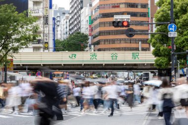 Tokyo, Japonya - 12 Mayıs 2024: İnsanlar Shibuya, Tokyo 'da işlek kavşağı geçiyor. Burası dünyanın en işlek kavşaklarından biri. (kasıtlı olarak insanların hareketlerini göstermek için bulanık)