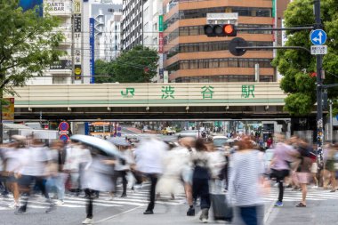 Tokyo, Japonya - 12 Mayıs 2024: İnsanlar Shibuya, Tokyo 'da işlek kavşağı geçiyor. Burası dünyanın en işlek kavşaklarından biri. (kasıtlı olarak insanların hareketlerini göstermek için bulanık)