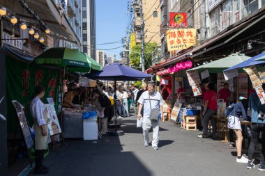 Tokyo, Japonya - 11 Mayıs 2024: İnsanlar Tokyo 'daki Tsukiji Dış Pazarı' nı ziyaret ediyor. Tsukiji Dış Pazarı bir gurme harikalar diyarı, özellikle de deniz ürünleri severler için.