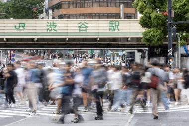 Tokyo, Japonya - 12 Mayıs 2024: İnsanlar Shibuya, Tokyo 'da işlek kavşağı geçiyor. Burası dünyanın en işlek kavşaklarından biri. (kasıtlı olarak insanların hareketlerini göstermek için bulanık)