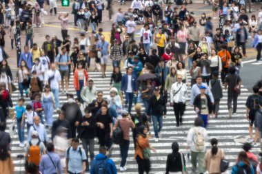 Tokyo, Japonya - 12 Mayıs 2024: İnsanlar Shibuya, Tokyo 'da işlek kavşağı geçiyor. Burası dünyanın en işlek kavşaklarından biri. (kasıtlı olarak insanların hareketlerini göstermek için bulanık)