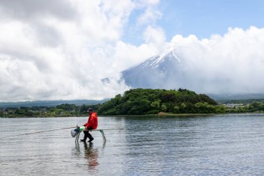 Kawaguchiko, Japonya-16 Mayıs 2024: Kawaguchiko Gölü 'nün berrak sularının üzerinde oturan Japon adam Fuji Dağı' nın arkasında, Fujikawaguchiko Dağı, Japonya.