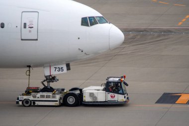 Tokyo, Japonya-19 Mayıs 2024: Önlük taşıyıcısı, Haneda Havaalanı, Tokyo 'daki havaalanı boyunca modern dar gövdeli beyaz yolcu uçağını çekiyor.