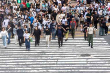 Tokyo, Japonya - 12 Mayıs 2024: İnsanlar Shibuya, Tokyo 'da işlek kavşağı geçiyor. Burası dünyanın en işlek kavşaklarından biri. (kasıtlı olarak insanların hareketlerini göstermek için bulanık)