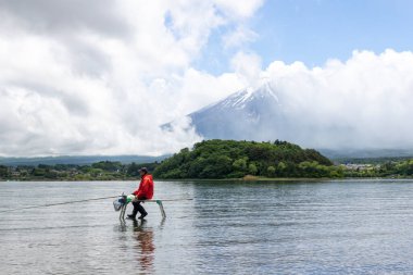 Kawaguchiko, Japonya-16 Mayıs 2024: Kawaguchiko Gölü 'nün berrak sularının üzerinde oturan Japon adam Fuji Dağı' nın arkasında, Fujikawaguchiko Dağı, Japonya.